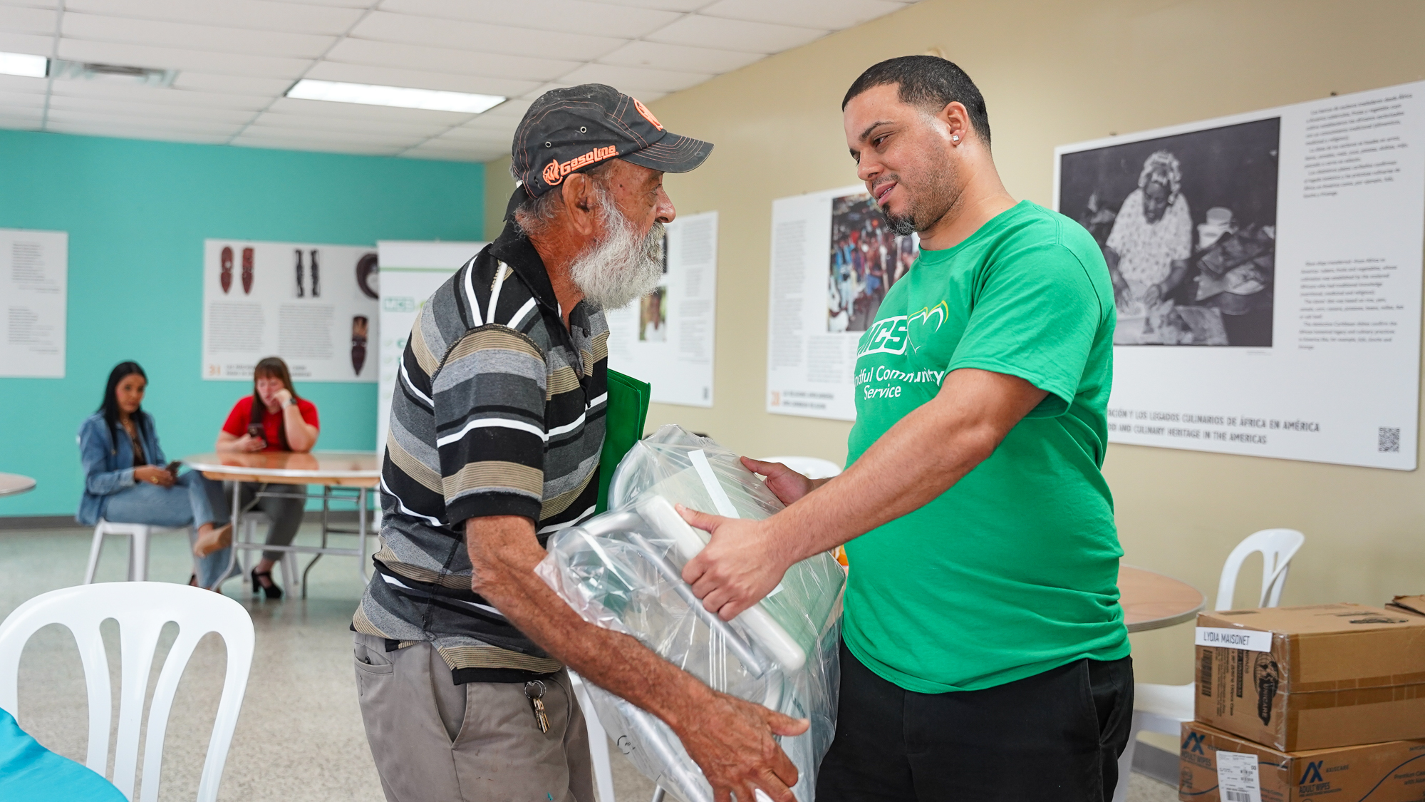 Participant of the MCS Mindful Community Program delivering food to an elderly woman in a community in Puerto Rico.
